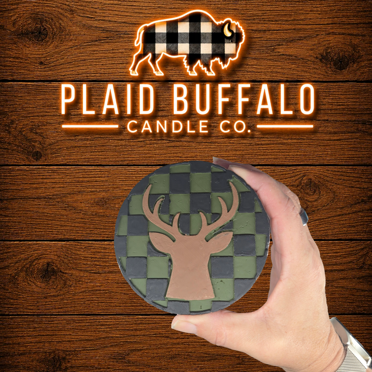 Round handmade deer silhouette car freshener featuring a green and charcoal buffalo plaid pattern, displayed on a rustic wood background.